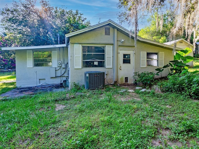 back of property with cooling unit and a lawn