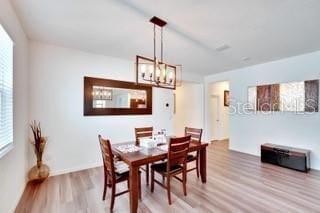 dining room with wood-type flooring and an inviting chandelier