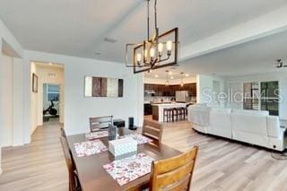 dining space with a chandelier and light hardwood / wood-style flooring