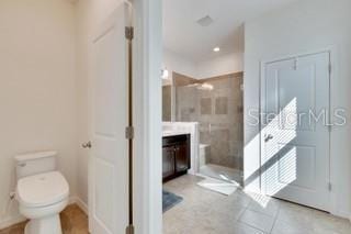 bathroom with vanity, toilet, and a tile shower