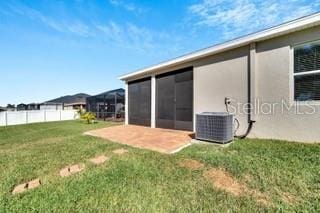 exterior space featuring cooling unit, a sunroom, a patio area, and a lawn