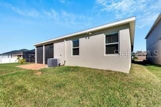 rear view of house with cooling unit, a patio, and a lawn