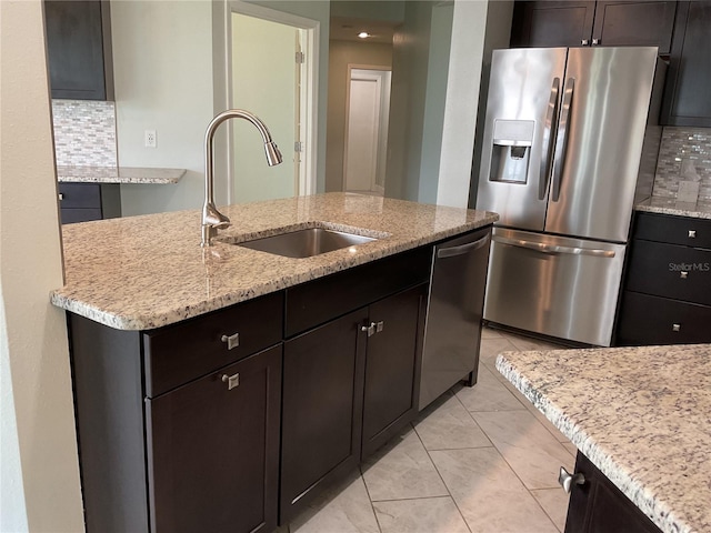 kitchen featuring appliances with stainless steel finishes, sink, decorative backsplash, light stone countertops, and light tile patterned flooring