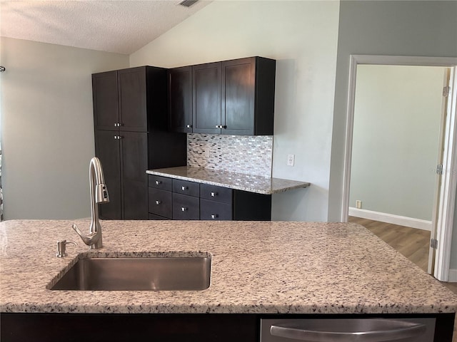 kitchen with hardwood / wood-style floors, sink, light stone counters, decorative backsplash, and lofted ceiling