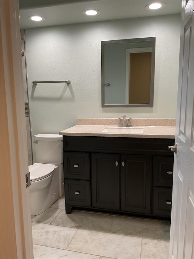 bathroom with toilet, vanity, and tile patterned flooring