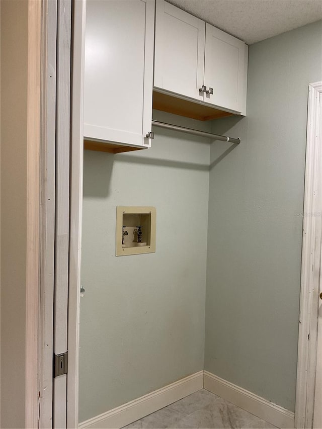 laundry room with washer hookup, a textured ceiling, and cabinets