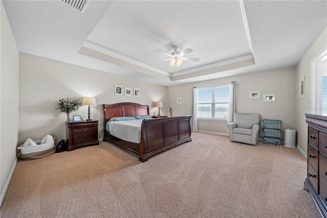 bedroom with light carpet, ceiling fan, and a raised ceiling