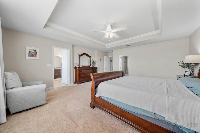 bedroom featuring light carpet, ensuite bath, ceiling fan, and a raised ceiling