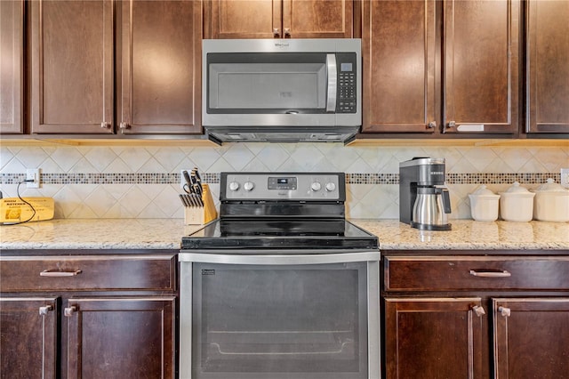 kitchen featuring appliances with stainless steel finishes, tasteful backsplash, and light stone counters