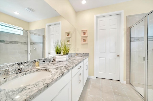 bathroom featuring dual vanity, a shower with shower door, and tile patterned flooring