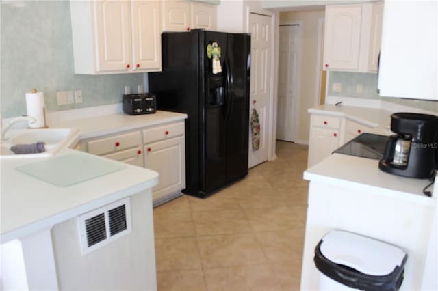 kitchen with light tile patterned flooring, black refrigerator with ice dispenser, white cabinetry, and sink