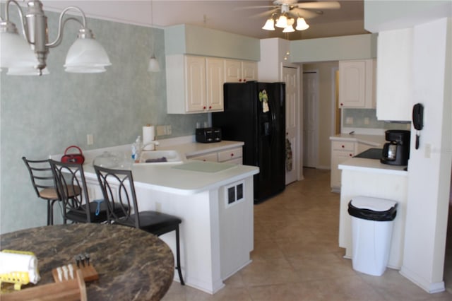 kitchen with light tile patterned floors, kitchen peninsula, ceiling fan, black fridge, and sink