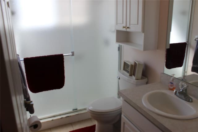 bathroom with vanity, walk in shower, tile patterned flooring, and toilet