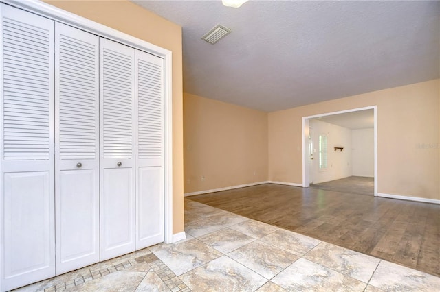 unfurnished bedroom featuring a closet, light wood-type flooring, and a textured ceiling