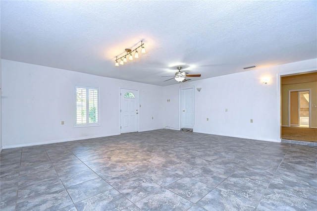 tiled empty room with rail lighting, a textured ceiling, and ceiling fan