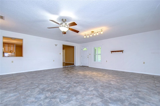 empty room with tile patterned flooring, a textured ceiling, rail lighting, and ceiling fan