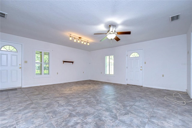 tiled foyer entrance with a textured ceiling, rail lighting, a wealth of natural light, and ceiling fan