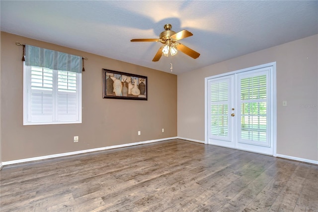 empty room with a healthy amount of sunlight, wood-type flooring, and ceiling fan