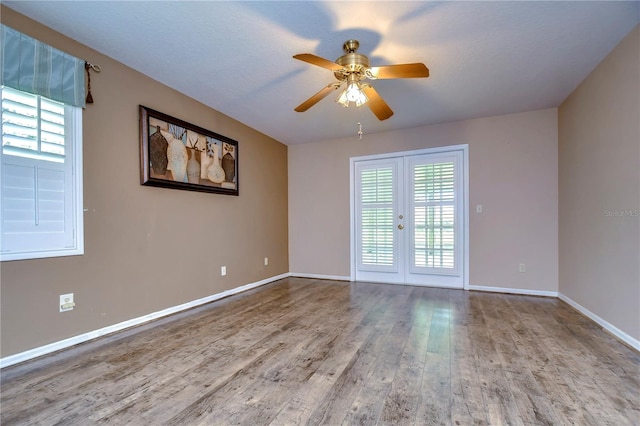 empty room with french doors, ceiling fan, wood-type flooring, and a wealth of natural light