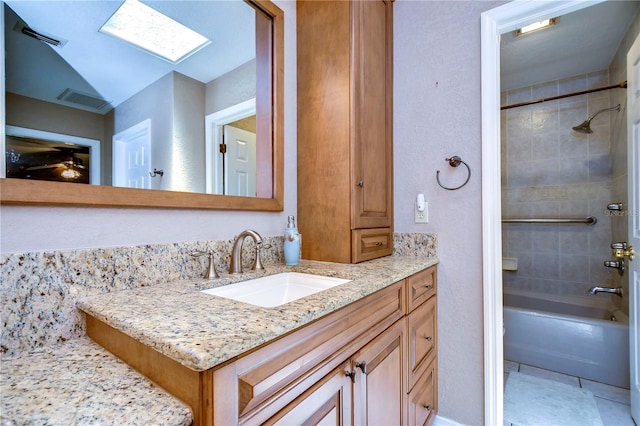 bathroom with a skylight, vanity, tiled shower / bath, and tile patterned flooring