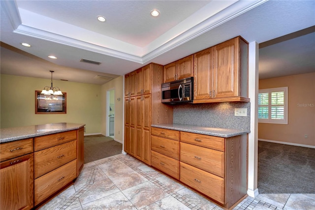 kitchen featuring an inviting chandelier, a tray ceiling, tasteful backsplash, and light tile patterned floors