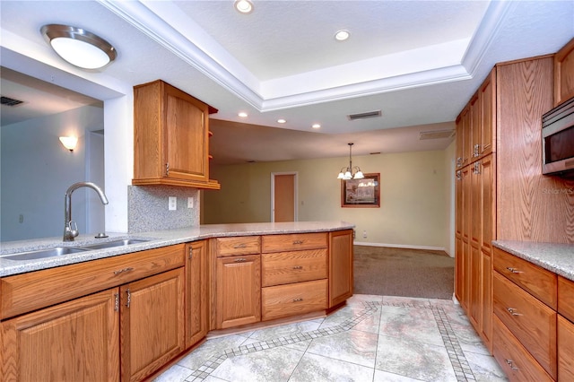 kitchen with light tile patterned floors, light stone countertops, hanging light fixtures, a raised ceiling, and sink