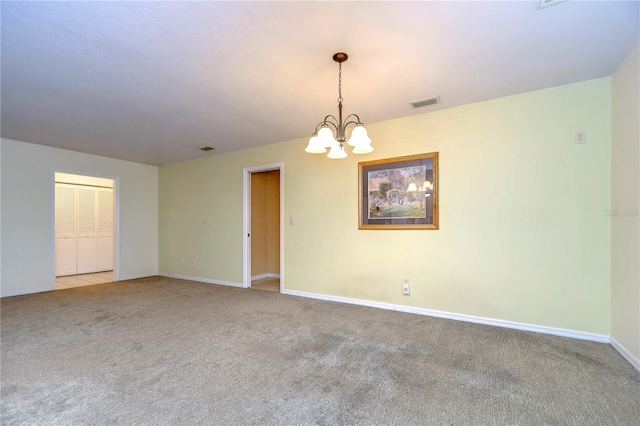 carpeted spare room featuring an inviting chandelier