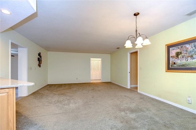 empty room with a notable chandelier and carpet