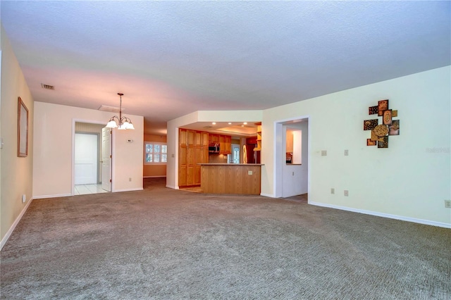 unfurnished living room featuring a chandelier, a textured ceiling, and light colored carpet