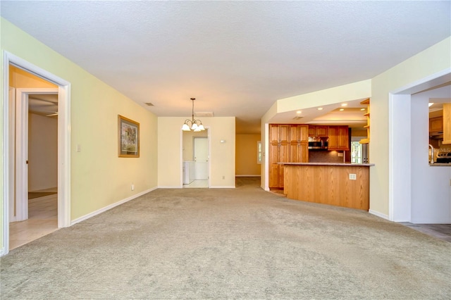 unfurnished living room with an inviting chandelier and light colored carpet