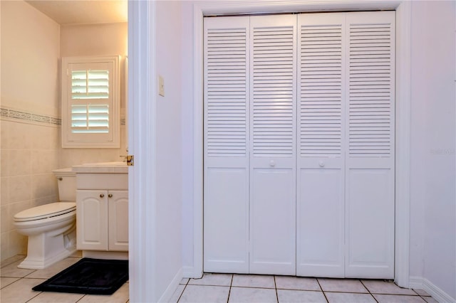 bathroom with tile patterned flooring, tile walls, toilet, and vanity