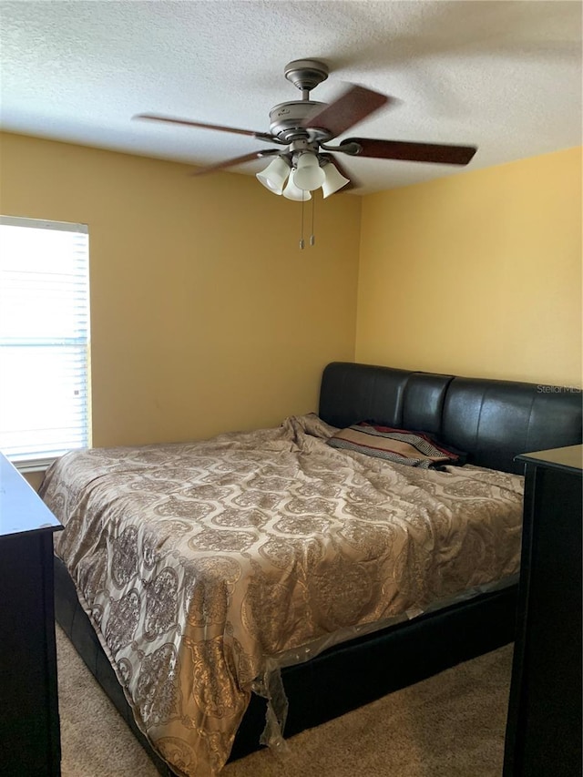 carpeted bedroom with ceiling fan and a textured ceiling