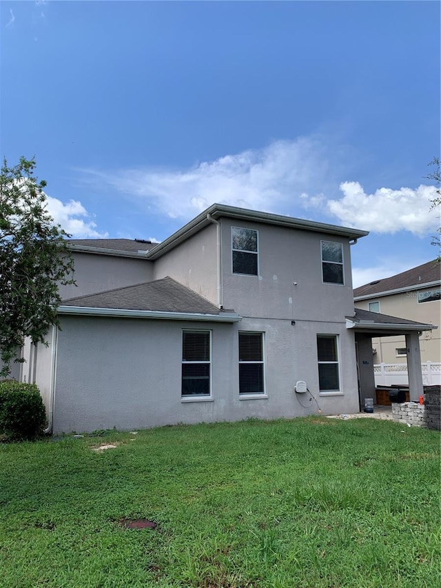 rear view of house featuring stucco siding and a yard