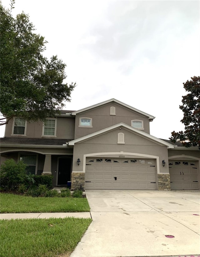 view of front facade featuring stucco siding, stone siding, a garage, and concrete driveway