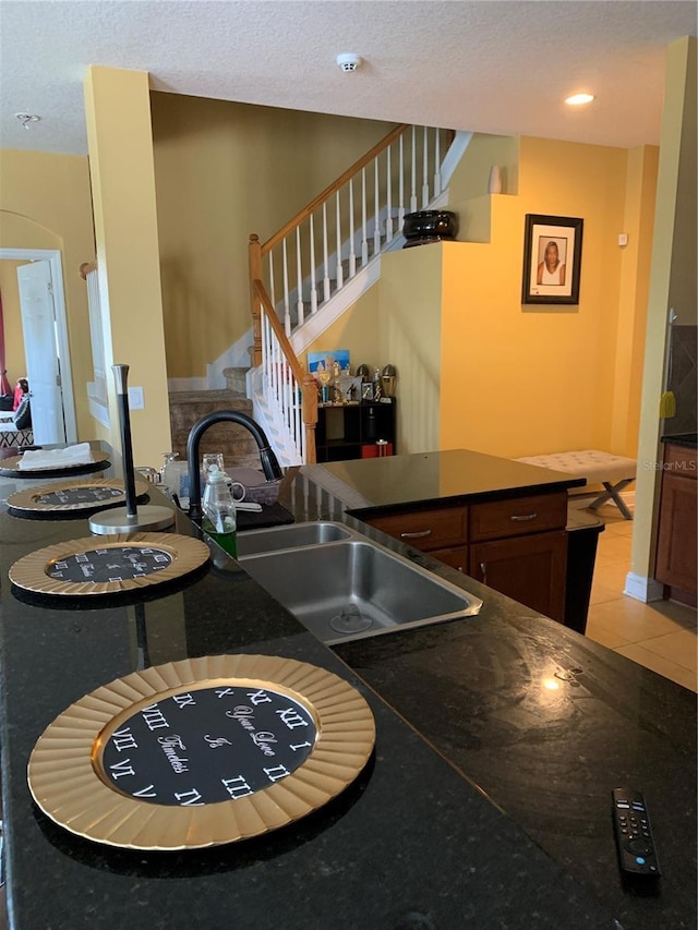 32502 Summerglade Dr, Wesley Chapel, FL 33545 - kitchen with a sink, dark countertops, a textured ceiling, light tile patterned floors, and a peninsula