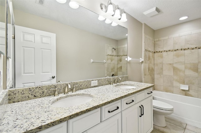 full bathroom with vanity, a textured ceiling, tiled shower / bath combo, tile patterned flooring, and toilet