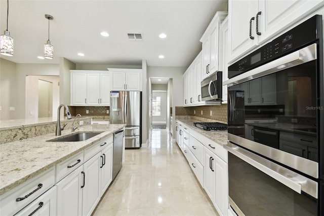 kitchen featuring decorative backsplash, appliances with stainless steel finishes, sink, white cabinetry, and hanging light fixtures