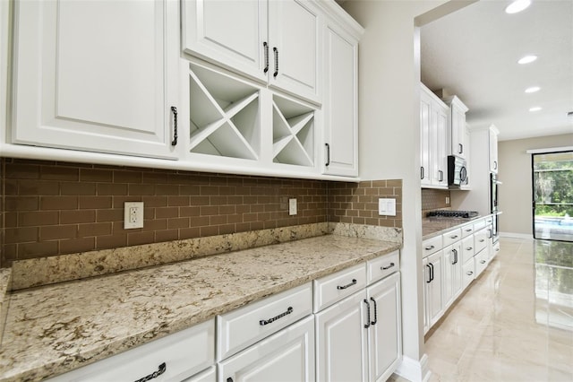 kitchen featuring white cabinets, decorative backsplash, light stone countertops, and appliances with stainless steel finishes