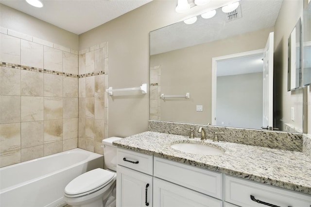 full bathroom featuring a textured ceiling, vanity, toilet, and tiled shower / bath