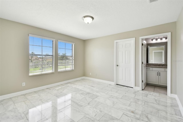 unfurnished bedroom featuring a textured ceiling and ensuite bath