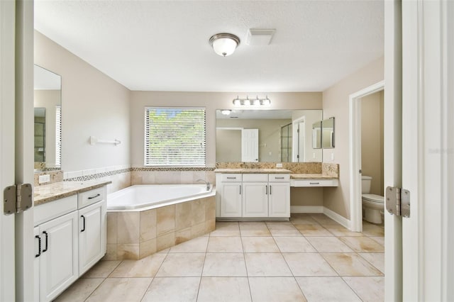 bathroom with tile patterned floors, a relaxing tiled tub, a textured ceiling, and toilet