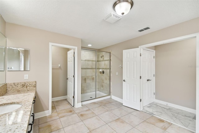 bathroom with vanity, an enclosed shower, and a textured ceiling