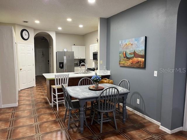 dining area with baseboards, visible vents, arched walkways, and recessed lighting