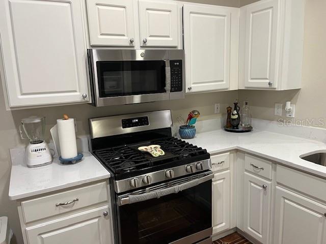 kitchen with appliances with stainless steel finishes, light countertops, and white cabinets