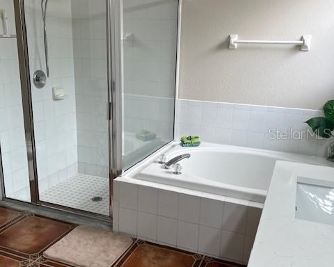 full bathroom featuring a garden tub, a shower stall, and tile patterned floors