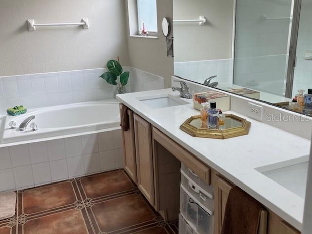 bathroom with vanity, tiled tub, and tile patterned flooring