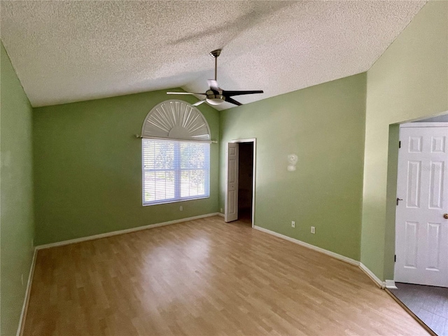 spare room with ceiling fan, a textured ceiling, lofted ceiling, and light wood-type flooring