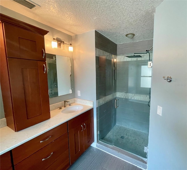 bathroom featuring a shower with shower door, vanity, tile patterned flooring, and a textured ceiling