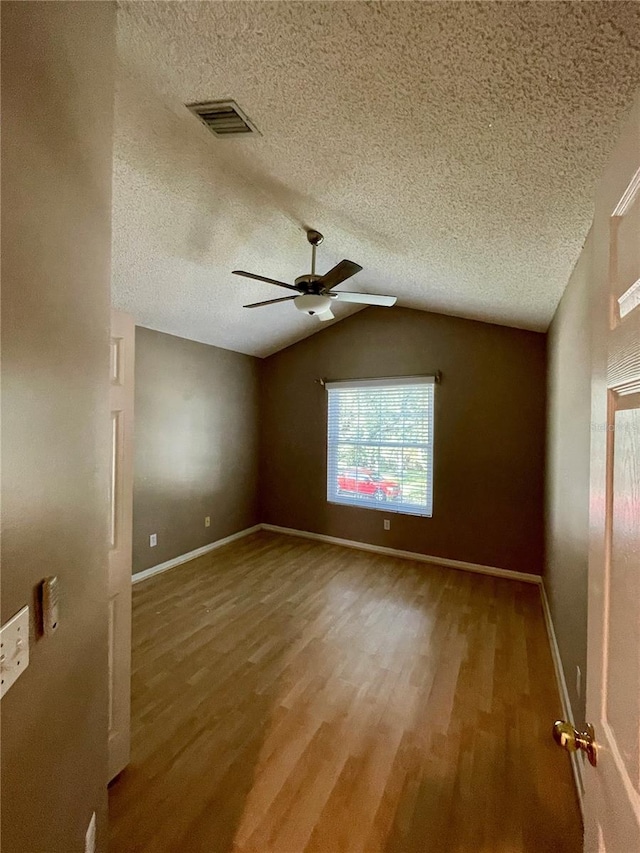 spare room featuring wood-type flooring, a textured ceiling, lofted ceiling, and ceiling fan