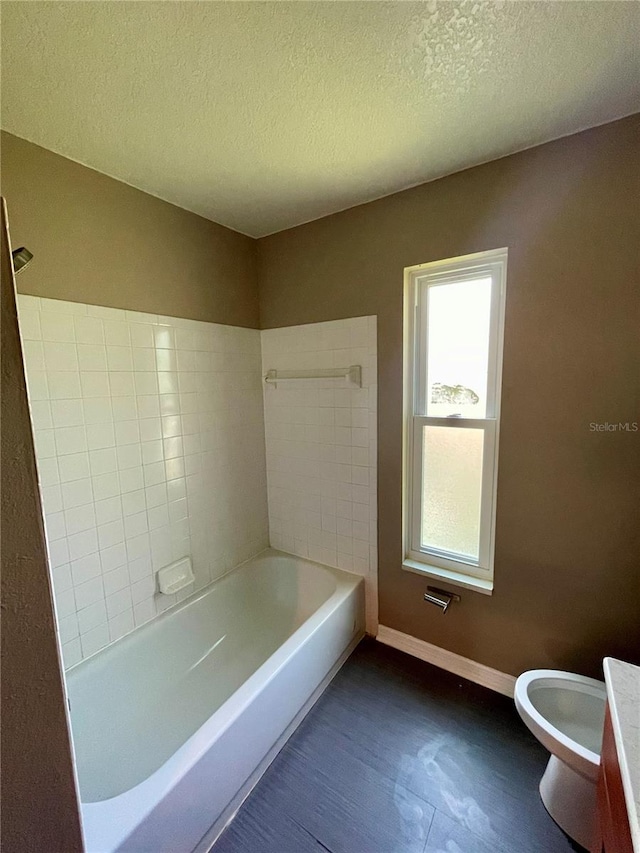 bathroom with shower / bathtub combination, a textured ceiling, and toilet